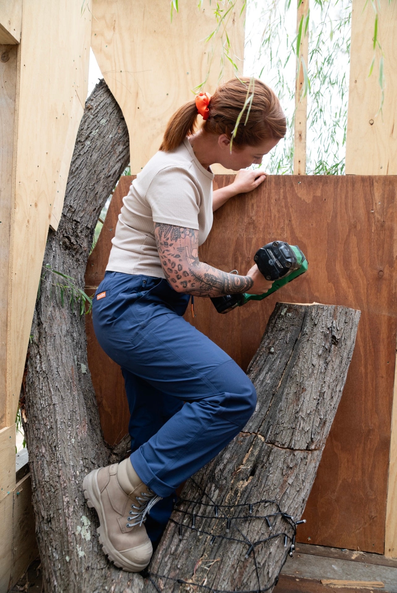 Woman modeling Zadie Workwear's black work pants, demonstrating flexibility and comfort.